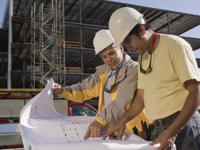 Construction workers with blueprints at construction site