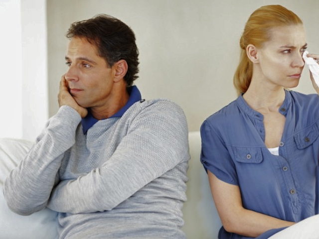 Portrait of angry couple with problems sitting on sofa