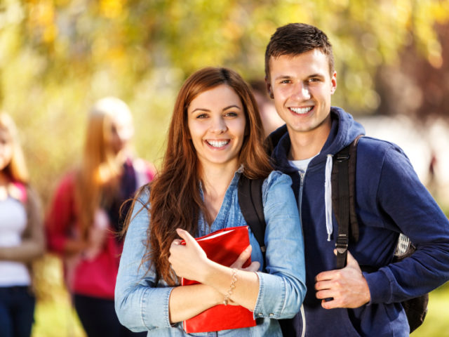 Two happy students in front of the campus