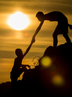 Silhouette of  helping hand of a friend with flare light.