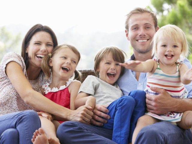 Family Sitting  On Garden Seat Together
